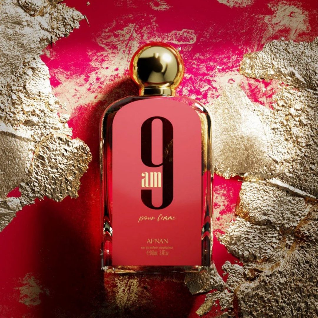 Pink perfume bottle with gold cap on a red and gold leafy background. Afnan 9am Pour Femme Womens Perfume
