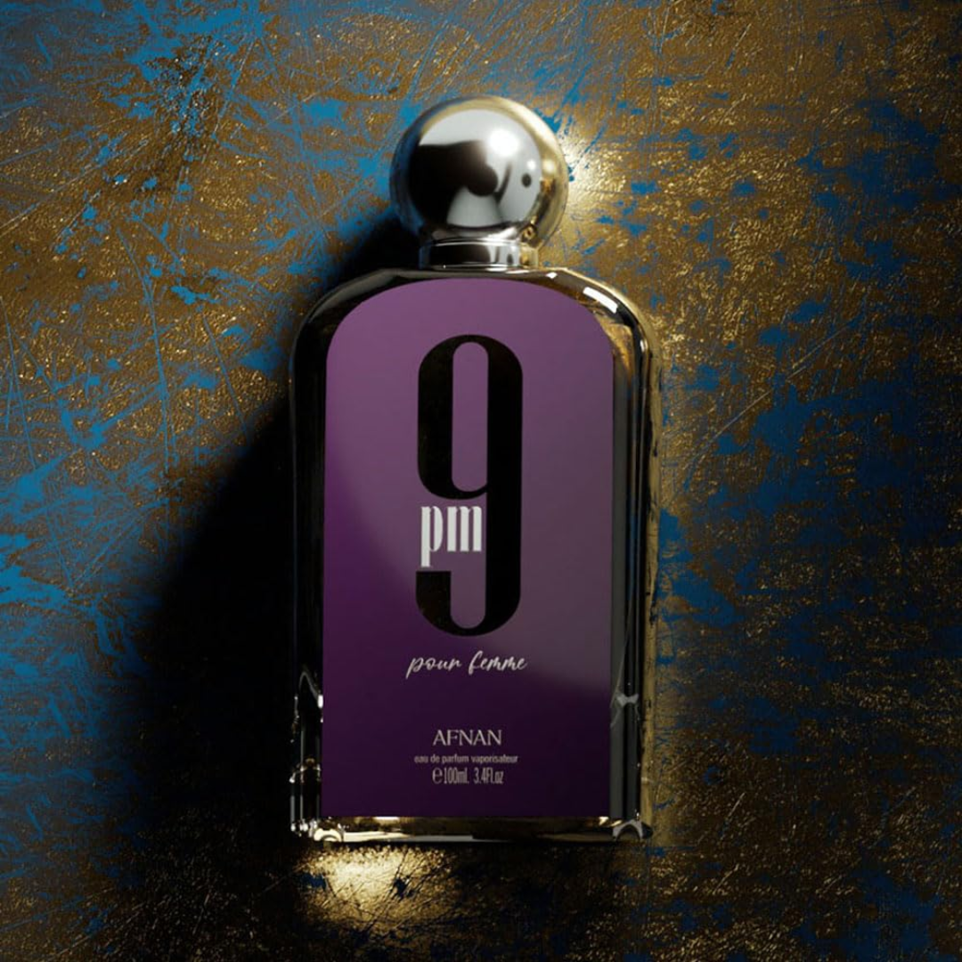 Perfume bottle with purple label and silver cap on a textured gold and blue background. Afnan 9pm Pour Femme Womens Perfume