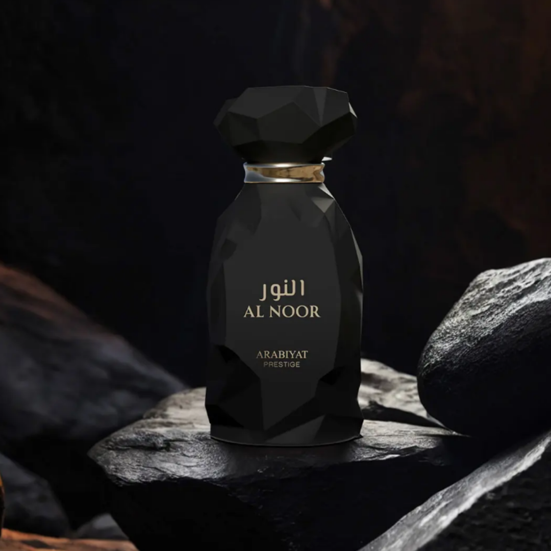 Black perfume bottle labeled 'Al Noor' on a dark rock background. Al Noor by Arabiyat Prestige Unisex Perfume
