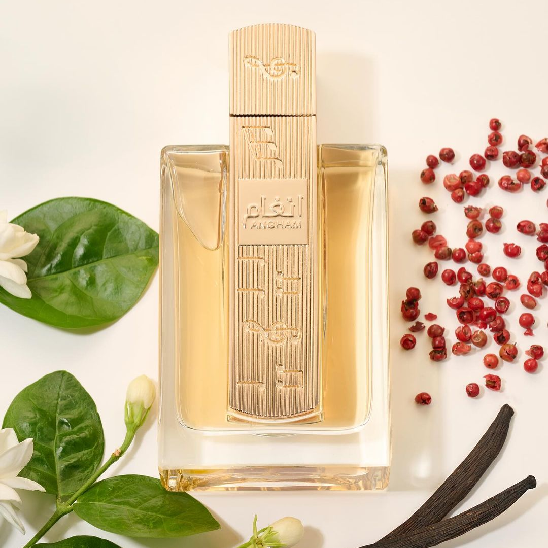 Perfume bottle with floral and spice elements on a light background. Angham by Lattafa 100ml perfume