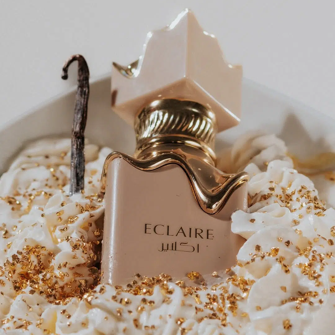 Perfume bottle with gold cap on a white cake with gold sprinkles. Eclaire Perfume by Lattafa. Clone / dupe of Bianco Latte by Giardini Di Toscana.