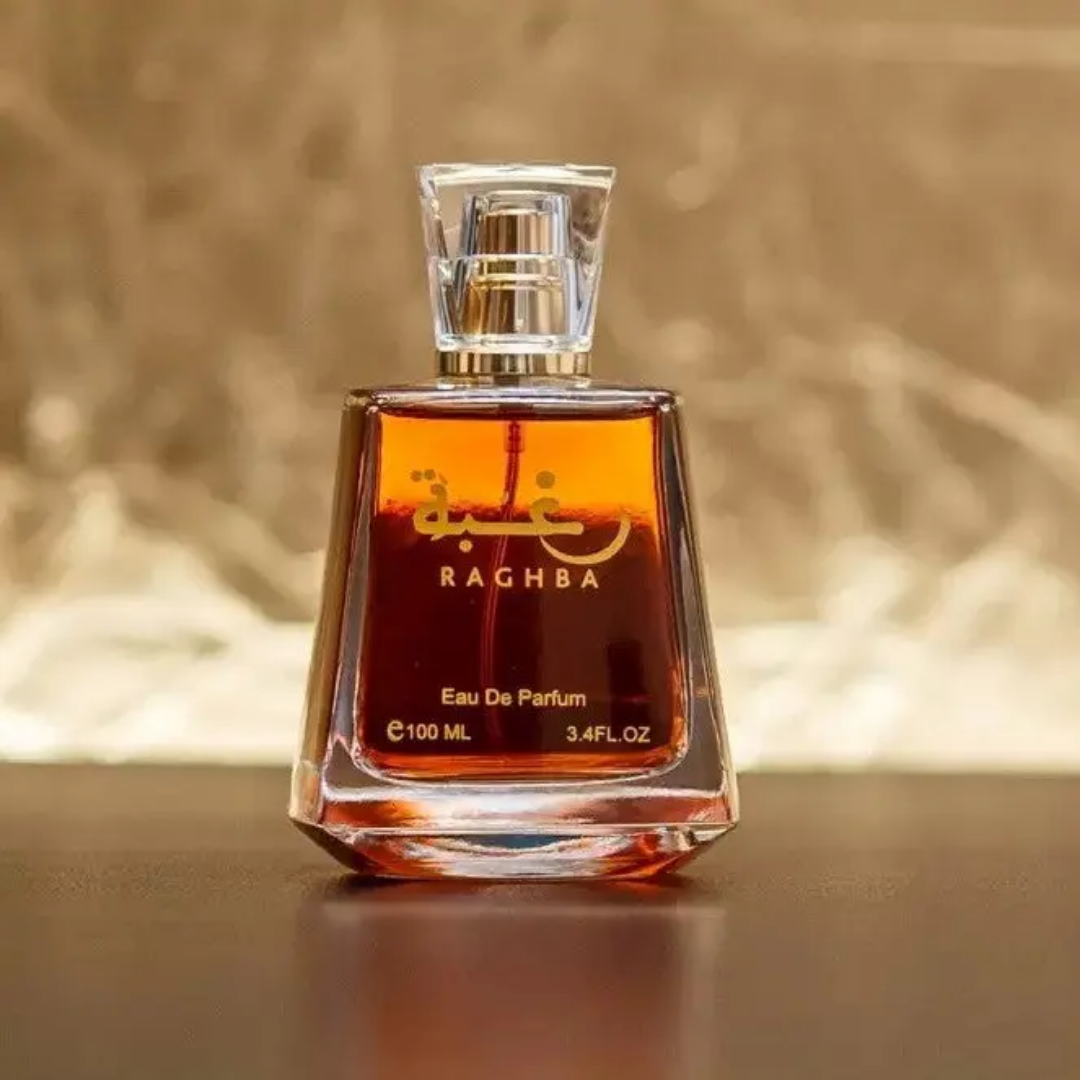 Perfume bottle labeled 'Raghba' on a reflective surface with a blurred background. Lattafa Raghba Unisex Perfume