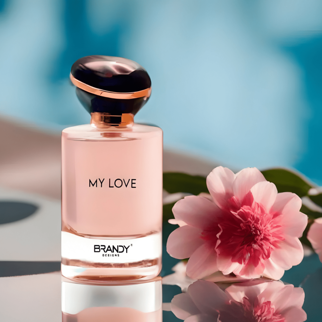 Perfume bottle labeled 'My Love' by Brandy with a pink flower on a reflective surface. My Love by Brandy Designs Womens Perfume.