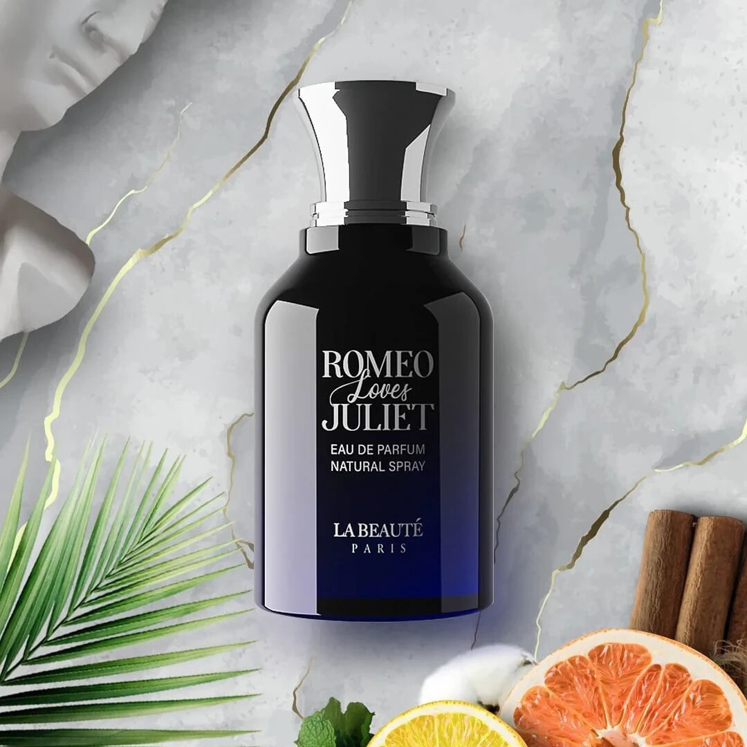 Perfume bottle labeled 'Romeo Loves Juliet' by La Beaute Paris on a decorative background with fruits and leaves.