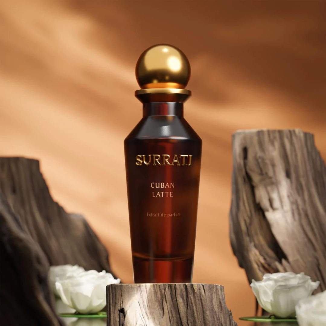 Surrati Cuban Latte perfume bottle with a gold cap on a wooden surface with white flowers.