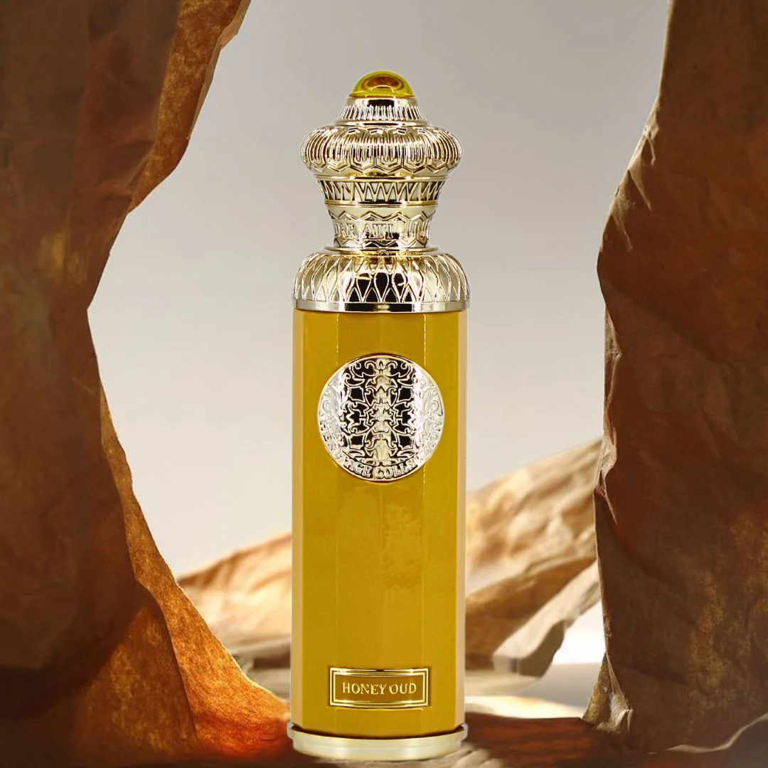 Yellow perfume bottle with intricate design on a textured background. Surrati Honey Oud Unisex Perfume
