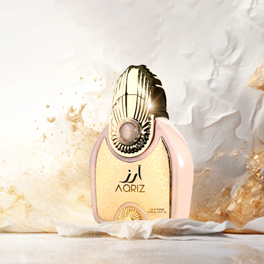 Perfume bottle with gold and white design on a textured background. Aariz by Arabiyat Prestige Unisex Perfume