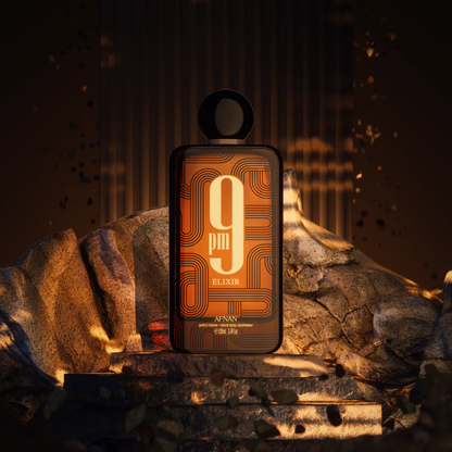 Perfume bottle labeled '9pm Elixir' by Afnan on a stone surface with a warm glow.