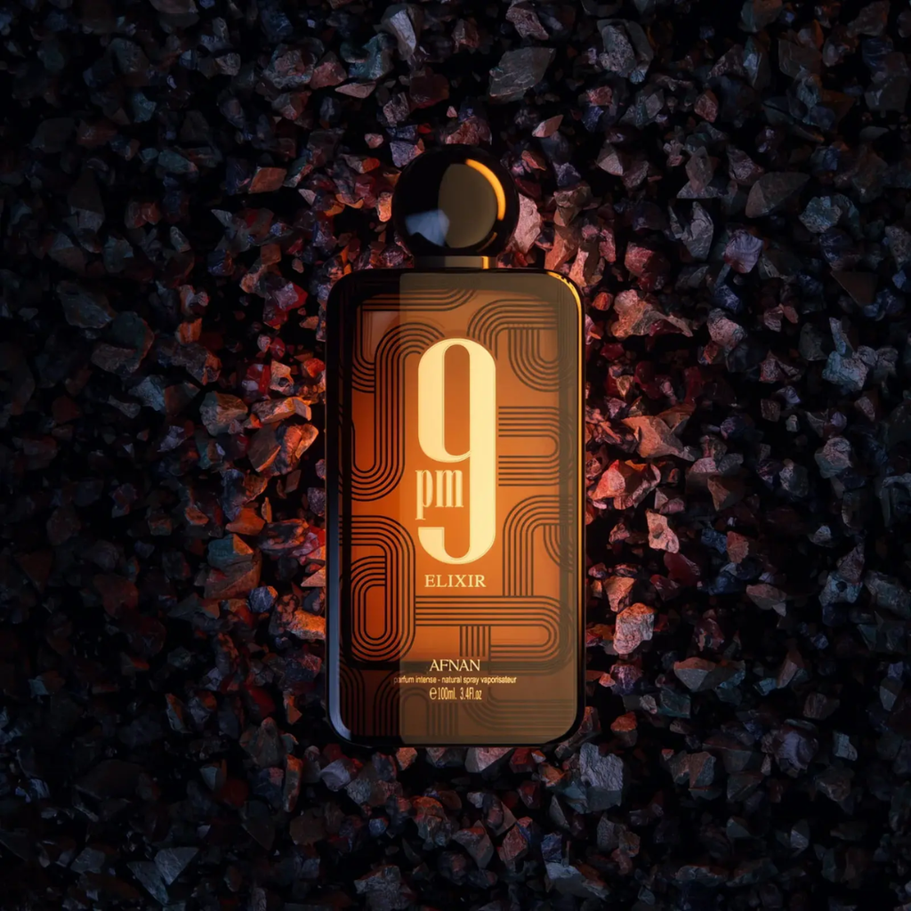 Perfume bottle labeled '9pm Elixir' by Afnan on a dark, textured surface.