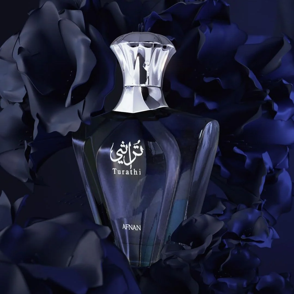 A dark glass perfume bottle with a reflective silver cap, labeled 'Turathi' and 'AFNAN', centered against a background of dark blue and black rose petals.