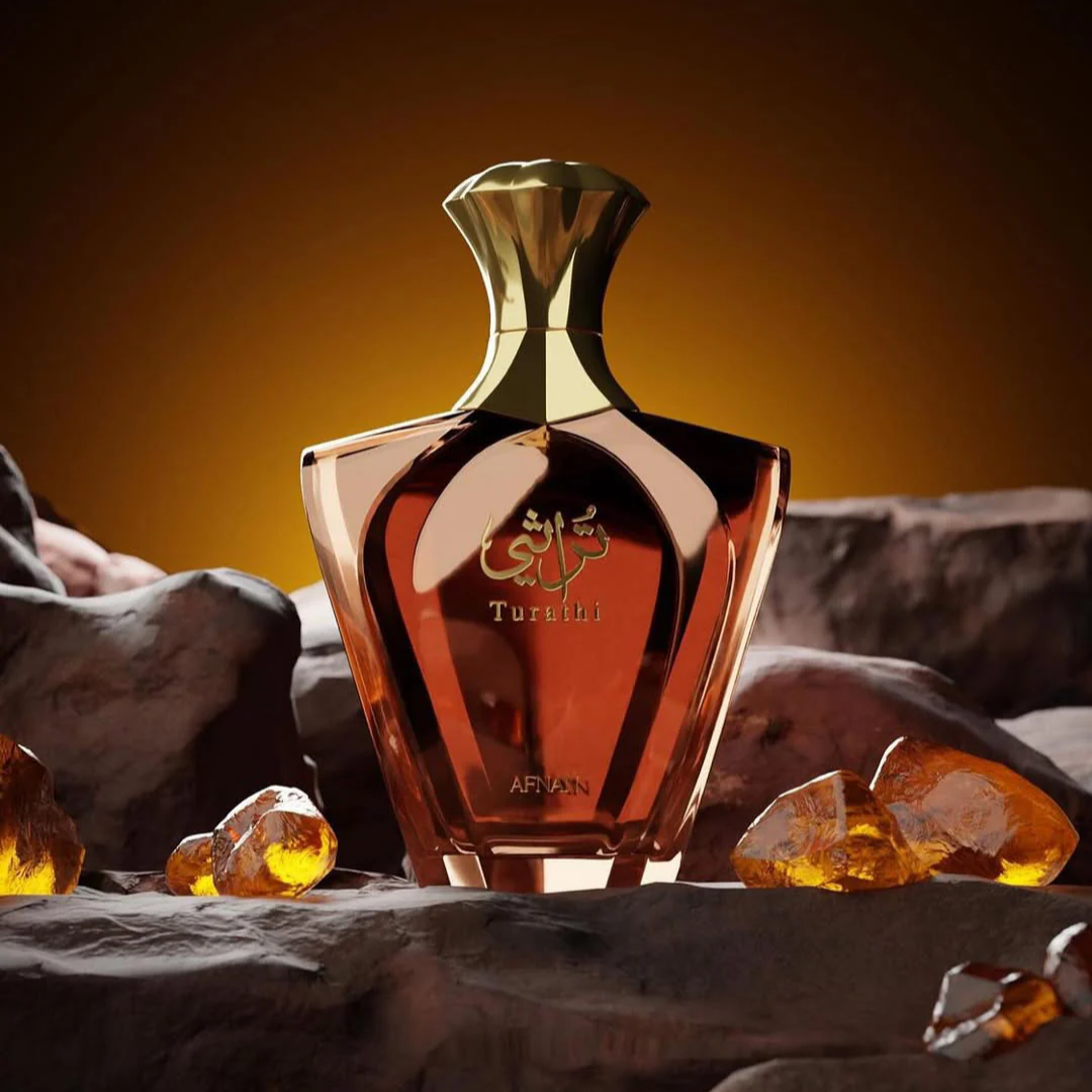 Afnan Turathi Brown perfume bottle with a gold cap and amber-brown faceted glass, displayed on dark rocks with glowing amber crystals against a warm brown background.