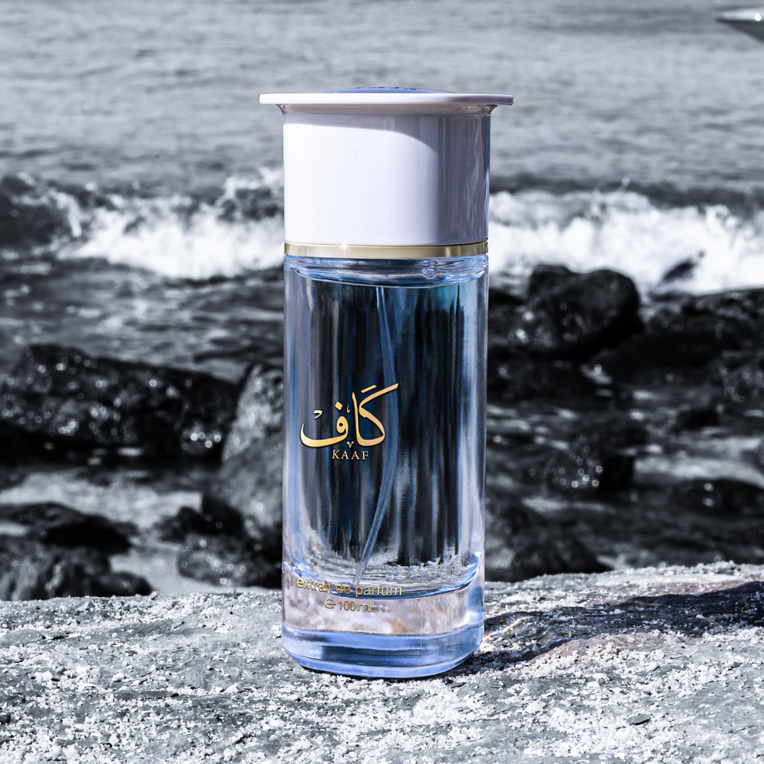 Perfume bottle with 'KAAF' branding on a rocky beach.
