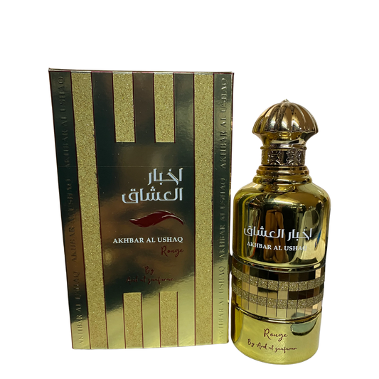 Gold perfume bottle and packaging with 'Akhbar Al Ushaq' branding on a reflective surface. Akhbar Al Ushaq Rouge by Ard Al Zaafaran Womens Perfume