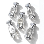 Five faceted silver perfume bottles arranged on a white background, each with a different abstract printed label design. The bottles are made of a reflective metallic material with geometric crystal-like tops and bases. Arabiyat Prestige: Marwa Extrait