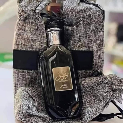 Mousuf Ramadi Eau de Parfum black edition – opulent Arabian fragrance in a sleek black glass bottle with silver cap, placed alongside an elegant grey drawstring pouch. Clone / dupe of / inspired by Jean Paul Gaultier - Ultra Male perfume.