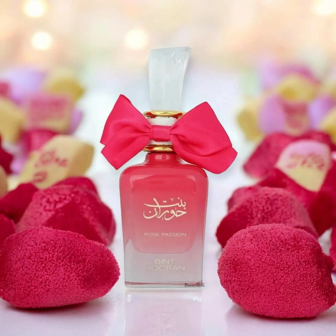Perfume bottle with a pink bow surrounded by pink hearts on a blurred background. Bint Hooran Rose Passion Womens Perfume by Ard Al Zaafaran