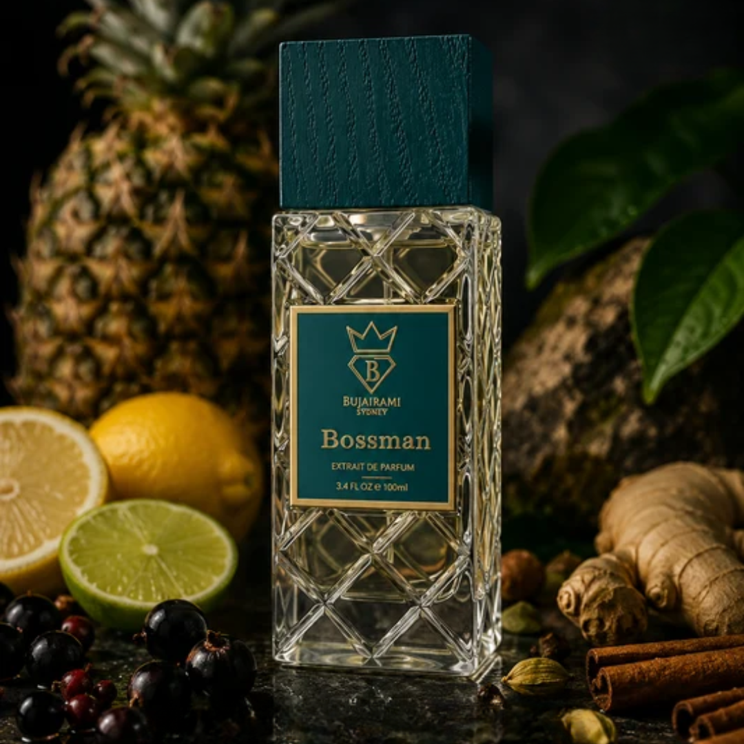 A bottle of Bossman perfume by Bujairami, styled with tropical ingredients including a pineapple, lemons, limes, ginger, cinnamon, and berries on a dark background.