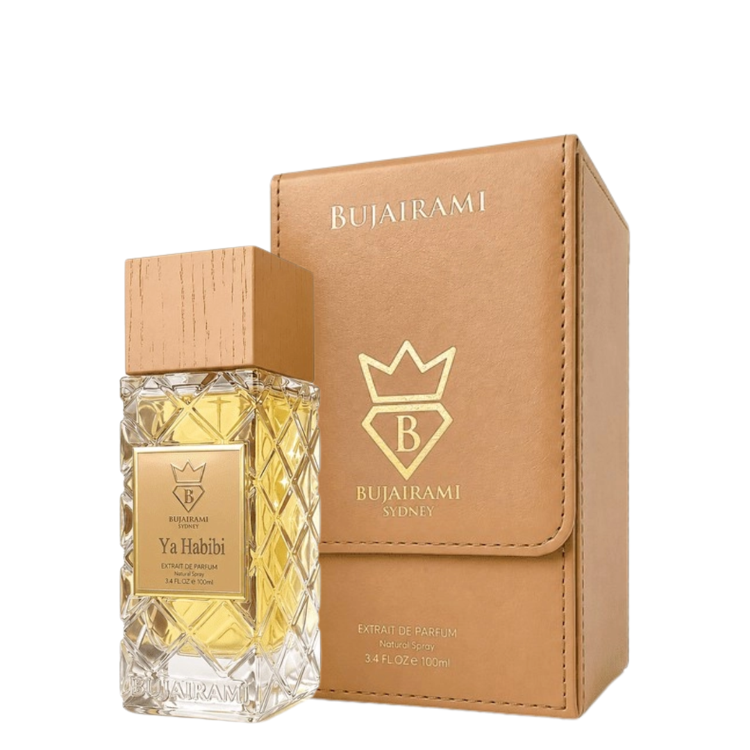 Bujairami Ya Habibi Extrait de Parfum bottle with a wooden cap next to its tan faux-leather box, both featuring gold branding on a white background.