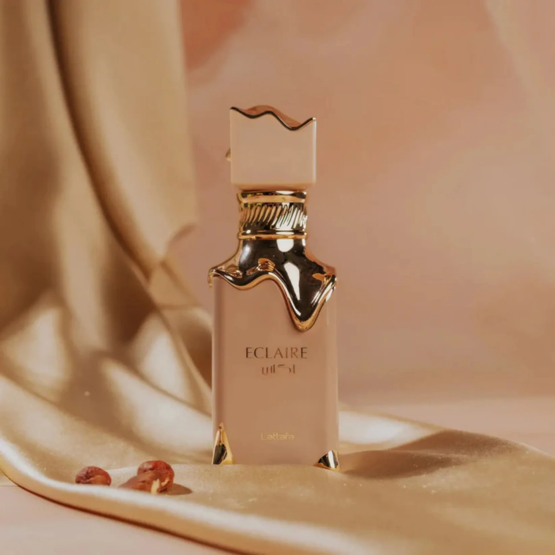 Perfume bottle labeled 'Eclaire' on a soft beige fabric background.  Eclaire Perfume by Lattafa. Clone / dupe of Bianco Latte by Giardini Di Toscana.