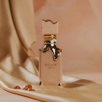 Perfume bottle labeled 'Eclaire' on a soft beige fabric background.  Eclaire Perfume by Lattafa. Clone / dupe of Bianco Latte by Giardini Di Toscana.