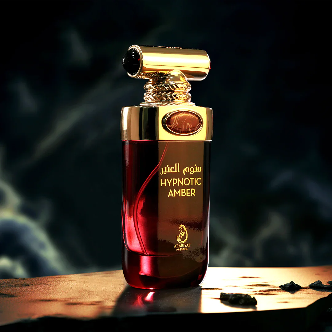 Perfume bottle labeled 'Hypnotic Amber' with a gold cap on a wooden surface. Hypnotic Amber by Arabiyat Prestige Unisex Perfume