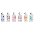 Six small rectangular bottles of IBRAQ fragrance oil arranged in a row on a plain white background. Each bottle has a white cap and a white body with a different colored label illustration and text. IBRAQ: Mini Summer Collection