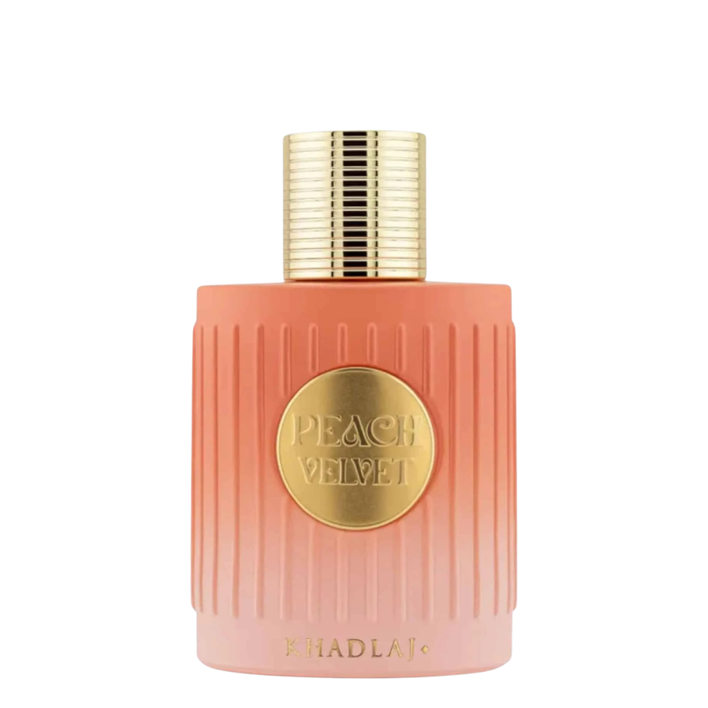 A bottle of Khadlaj Peach Velvet perfume with a ribbed peach-pink bottle, a gold circular label, and a textured gold cap, set against a plain white background.