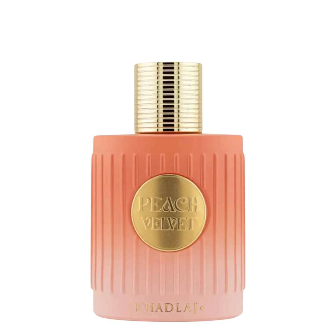 A bottle of Khadlaj Peach Velvet perfume with a ribbed peach-pink bottle, a gold circular label, and a textured gold cap, set against a plain white background.