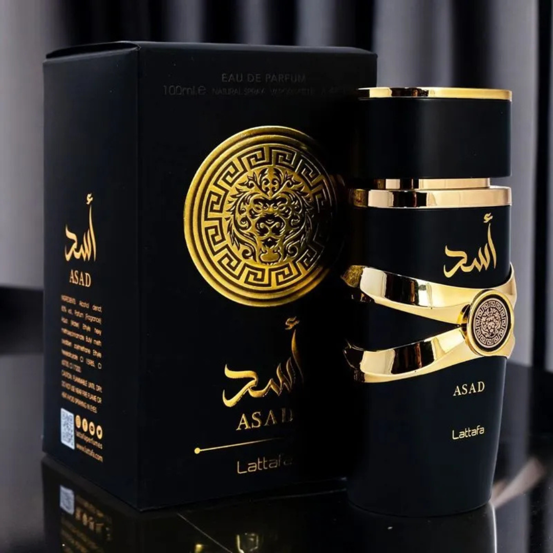 Asad by Lattafa perfume with luxury box – Matte black fragrance bottle with golden details beside matching gold-accented packaging on a reflective black surface. 