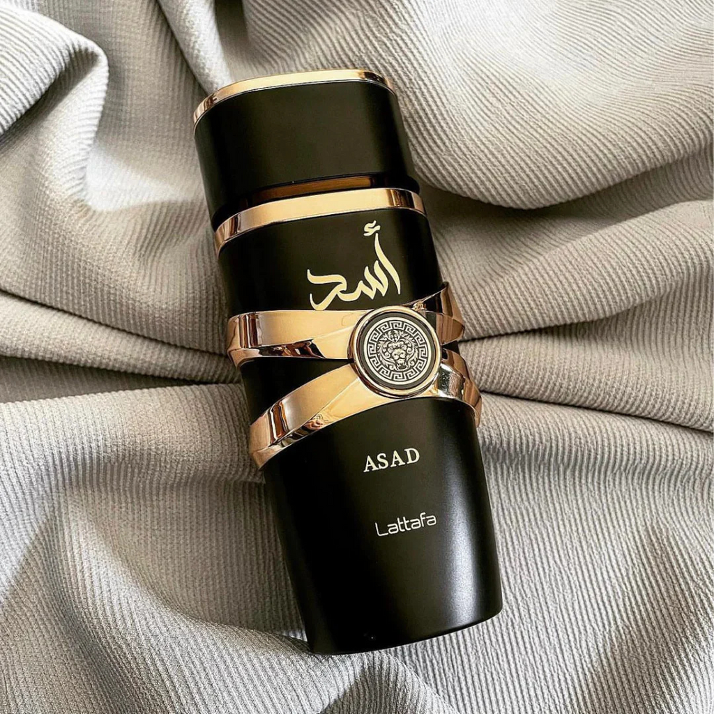 Asad by Lattafa perfume on fabric – Stylish black and gold bottle resting on soft beige textured fabric. 