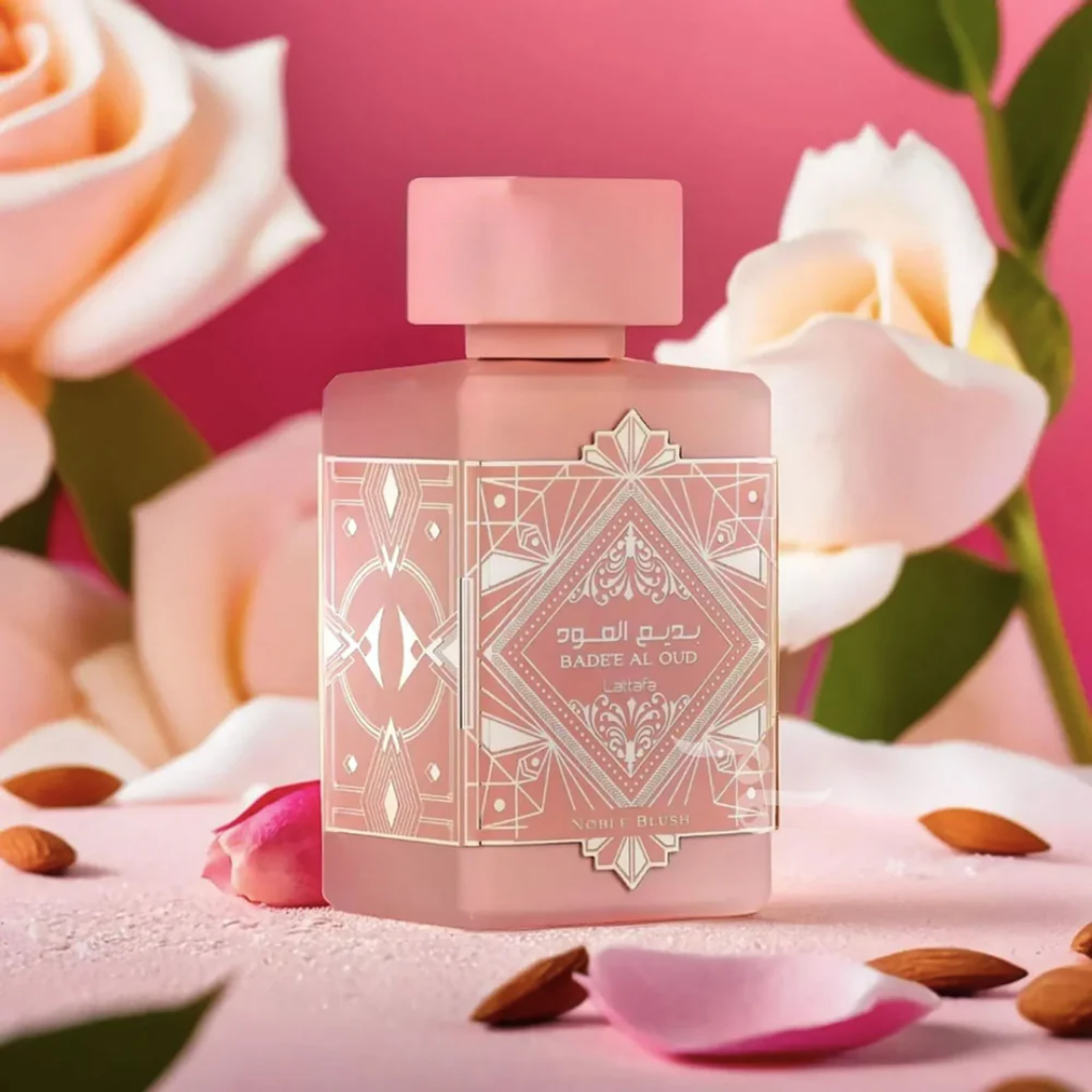 Pink perfume bottle with decorative label on a pink floral background. Lattafa Badee Al Oud Noble Blush Unisex Perfume