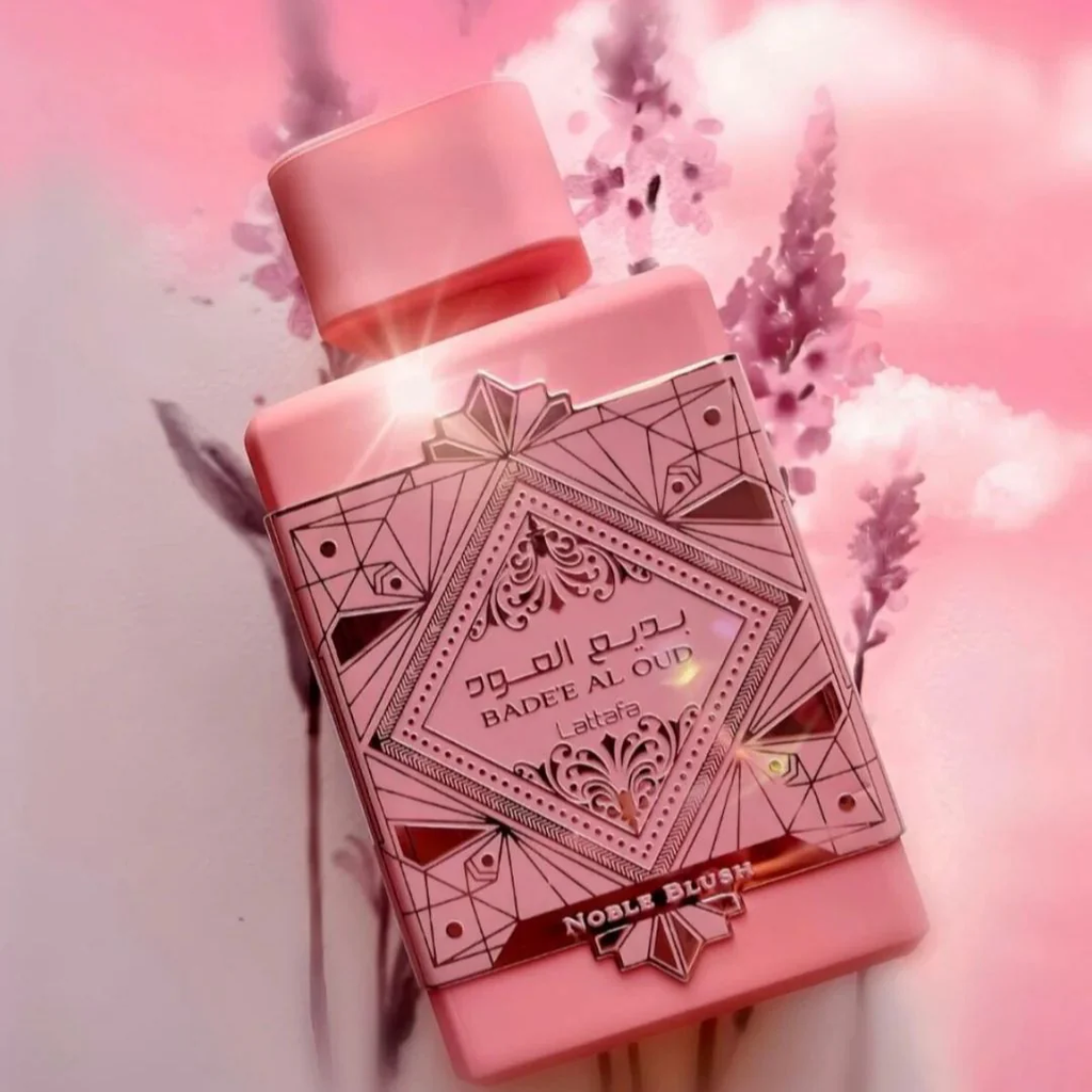 Pink perfume bottle with intricate designs on a pink background with flowers. Lattafa Badee Al Oud Noble Blush Unisex Perfume