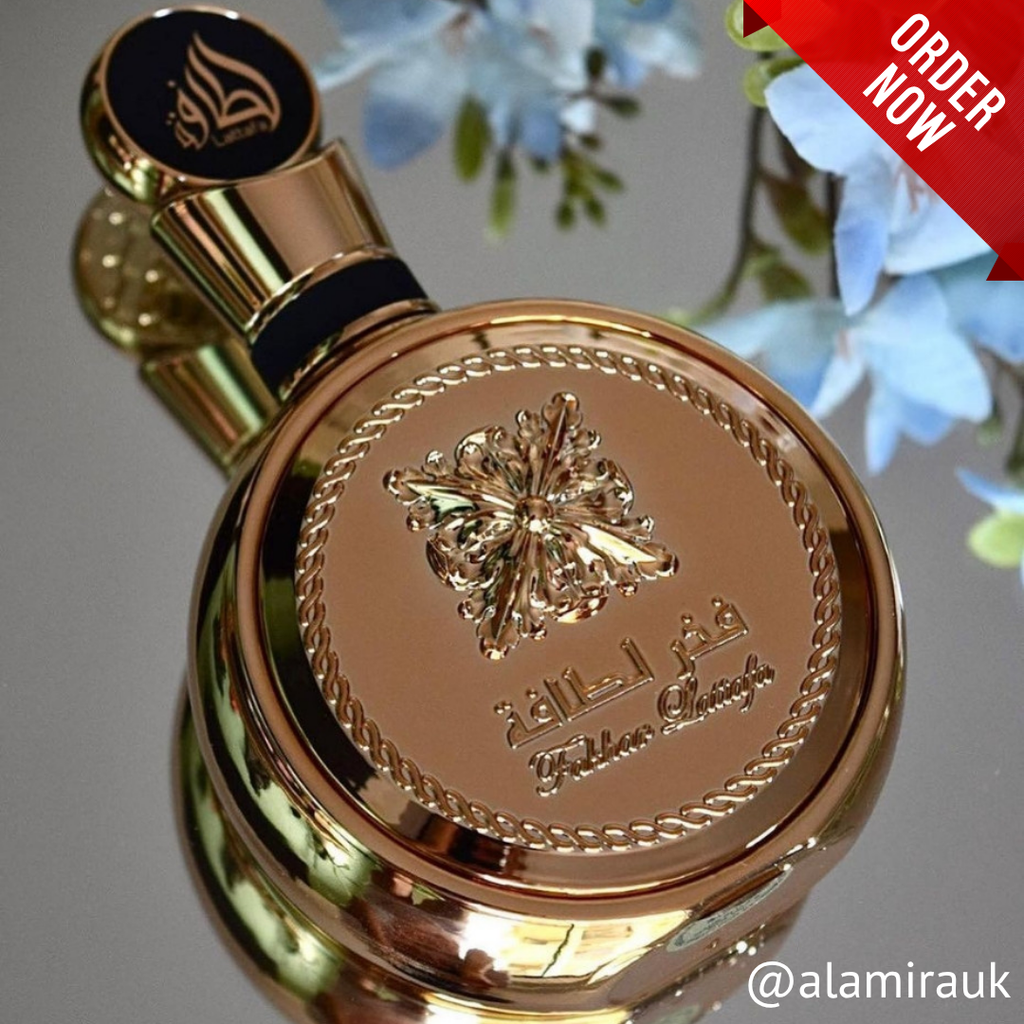 Gold perfume bottle with decorative design and 'Golden Shaheen' branding against a blurred floral background. 