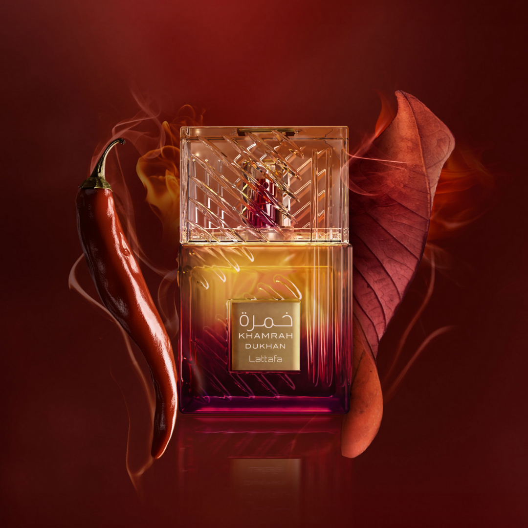 Lattafa Khamrah Dukhan Eau de Parfum surrounded by red chili pepper and autumn leaves – bold smoky-spicy unisex fragrance with warm oriental undertones.