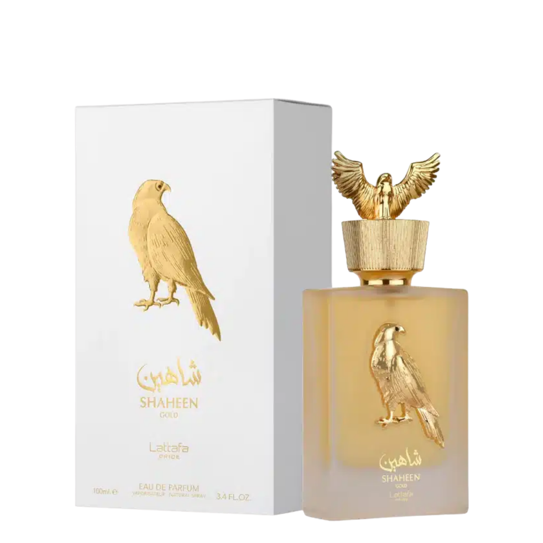 Lattafa: Shaheen Gold perfume bottle and its white packaging box, both featuring a gold falcon illustration and a metallic gold eagle cap on a white background.