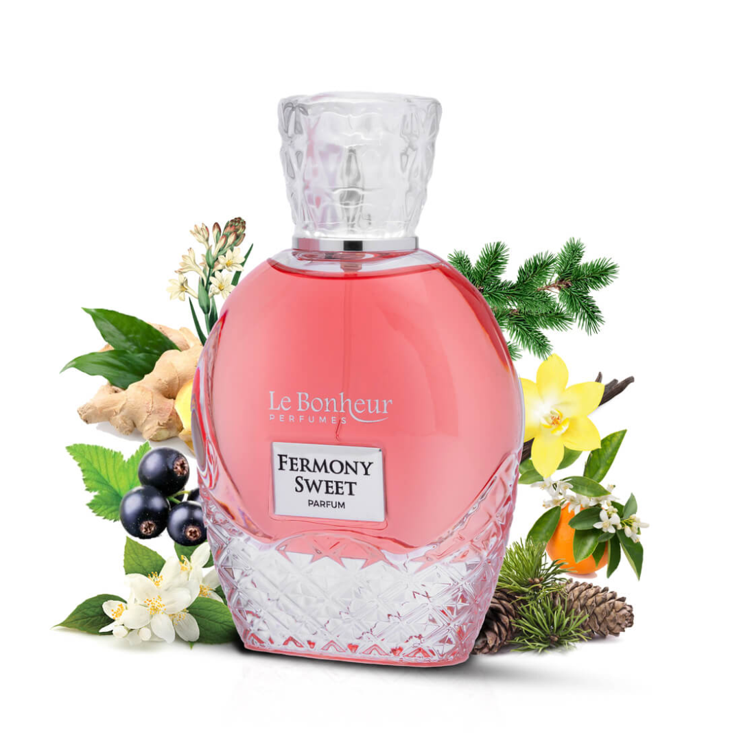 Le Bonheur Parfums 'Fermony Sweet' perfume bottle, pink with a clear faceted cap and base, surrounded by decorative botanical elements like pine branches, white flowers, blackberries, ginger, and a pinecone on a white background.