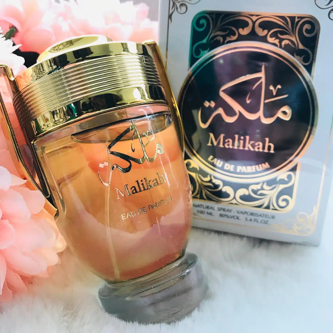 Malikah perfume bottle and packaging on a soft white background with pink flowers. Malikah Womens Perfume by Ard Al Zaafaran