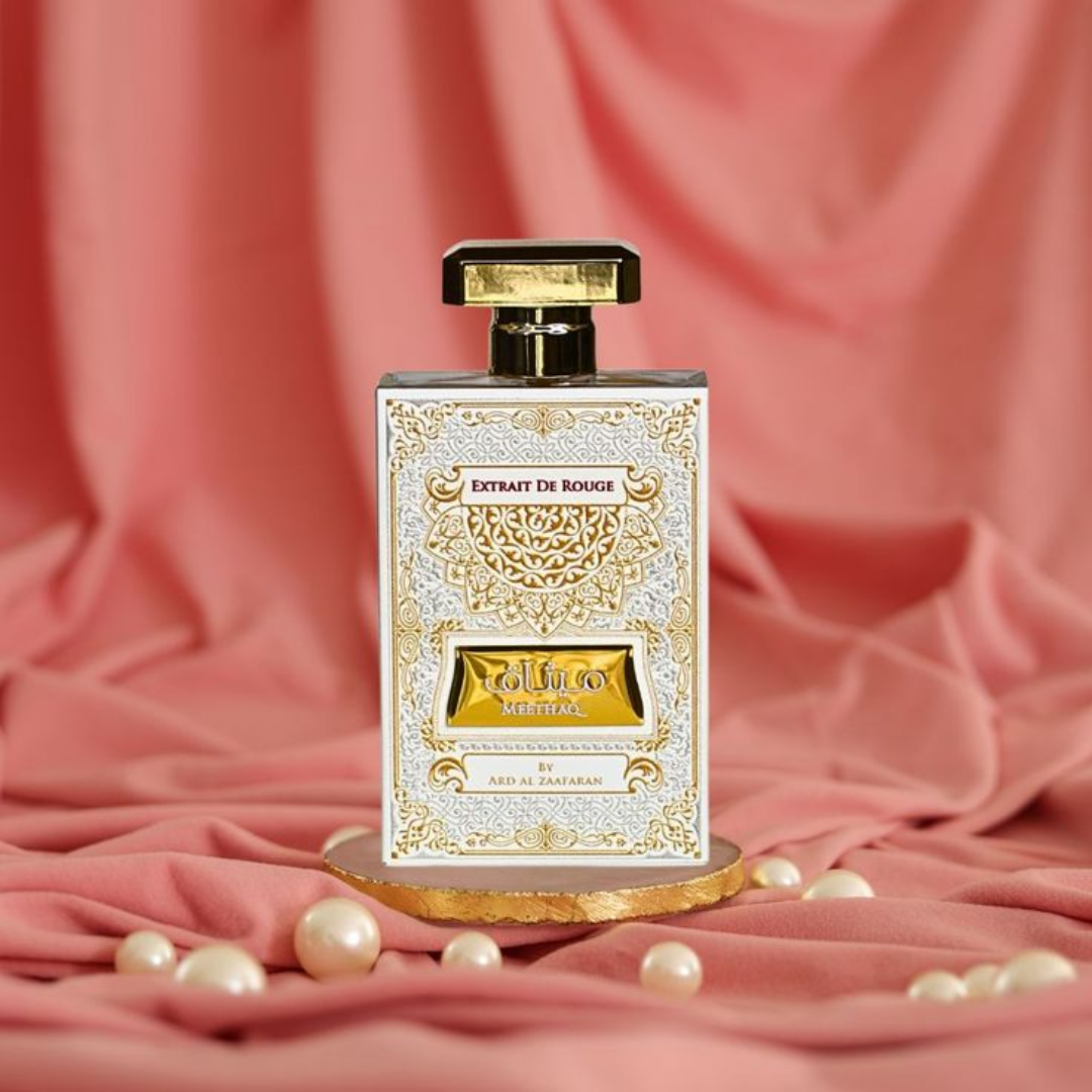 Perfume bottle with decorative label on a pink fabric background. Meethaq Extrait De Rouge by Ard Al Zaafaran Womens Perfume