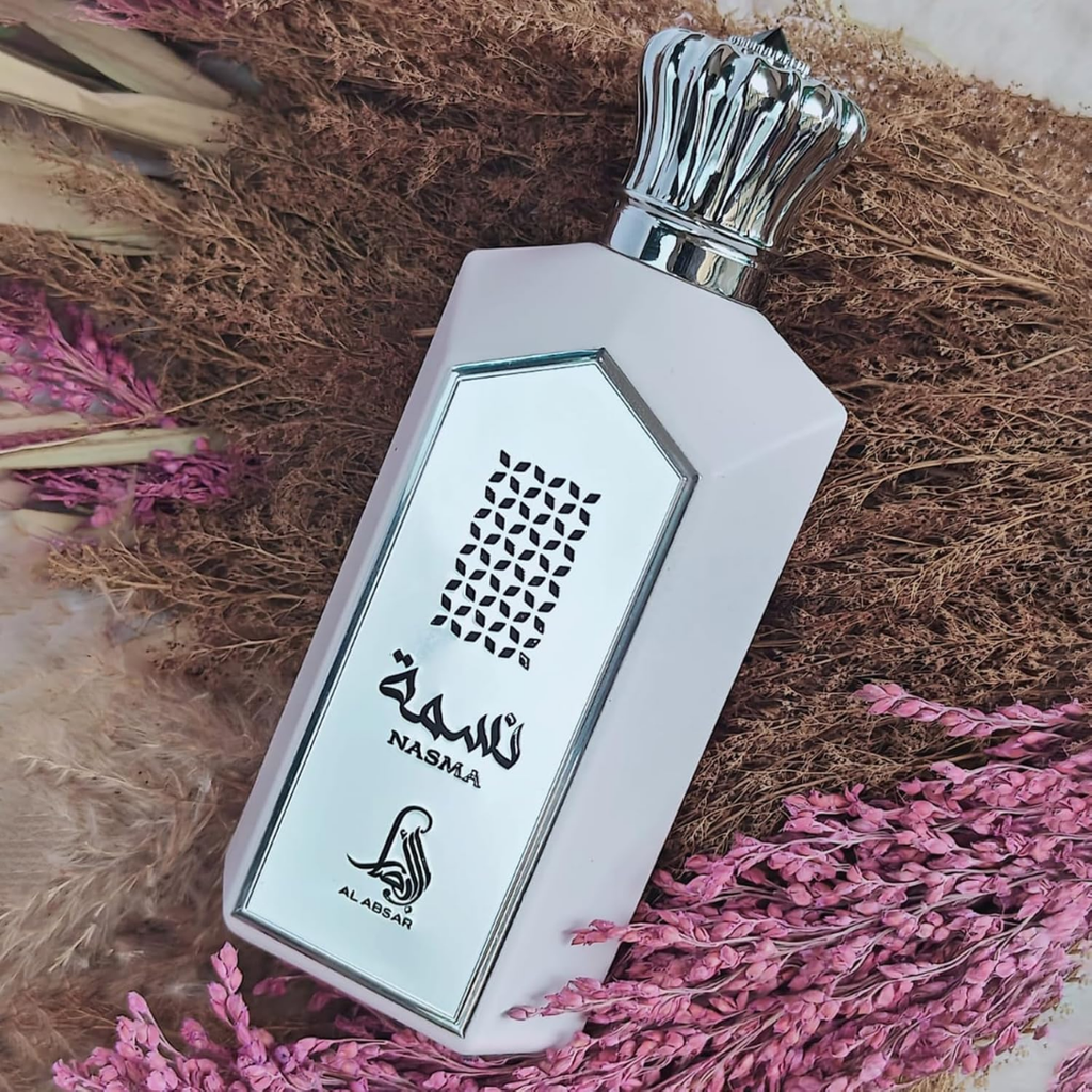 Perfume bottle with 'Nasma' branding on a textured surface with pink flowers