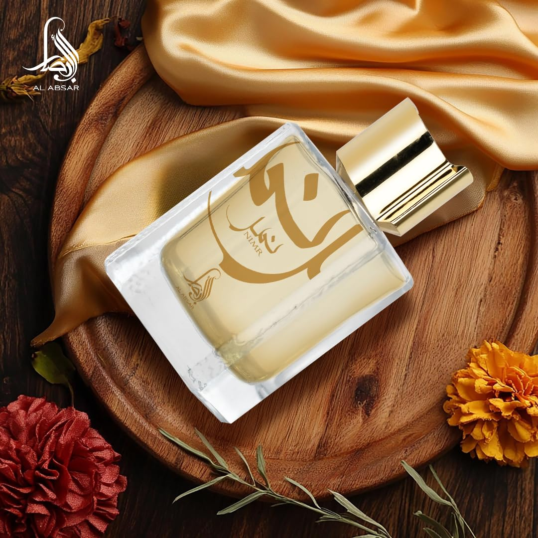 Perfume bottle with gold accents on a wooden tray with fabric and flowers