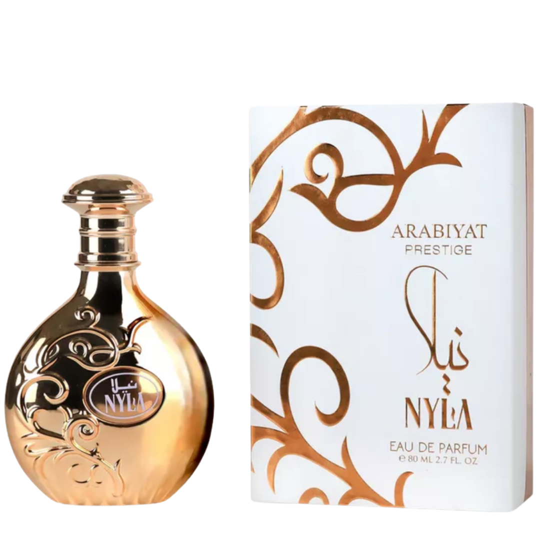 A product image featuring Nyla Perfume by Arabiyat Prestige, with an 80ml Eau De Parfum bottle on the left and its packaging on the right. The bottle is gold-colored with floral patterns and a clear label, while the packaging has white and gold designs with the brand and product name, women perfumes.