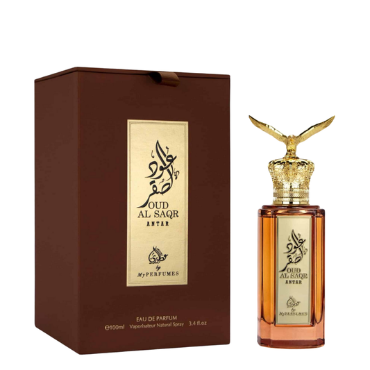 A perfume bottle of Oud Al Saqr Antar Eau de Parfum by My Perfumes, with a gold-colored cap and a brown box packaging. Premium Oud Al Saqr Antar perfume bottle with amber glass, intricate golden eagle cap, and gold-plated Arabic calligraphy label.