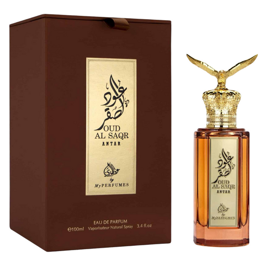 A perfume bottle of Oud Al Saqr Antar Eau de Parfum by My Perfumes, with a gold-colored cap and a brown box packaging. Premium Oud Al Saqr Antar perfume bottle with amber glass, intricate golden eagle cap, and gold-plated Arabic calligraphy label.