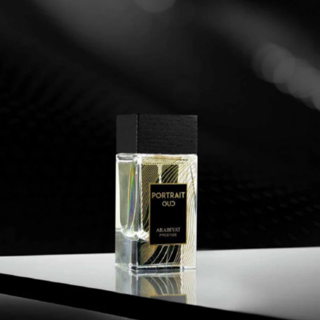 Perfume bottle labeled 'Portrait Oud' by Ahabiyat on a reflective surface with a dark background. Portrait Oud by Arabiyat Prestige Unisex Perfume