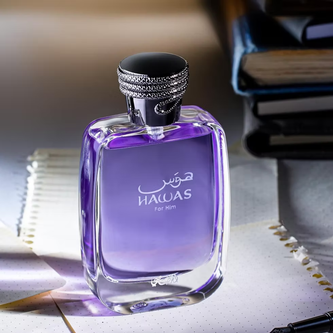 Purple perfume bottle labeled 'Hawas' on a surface with books in the background