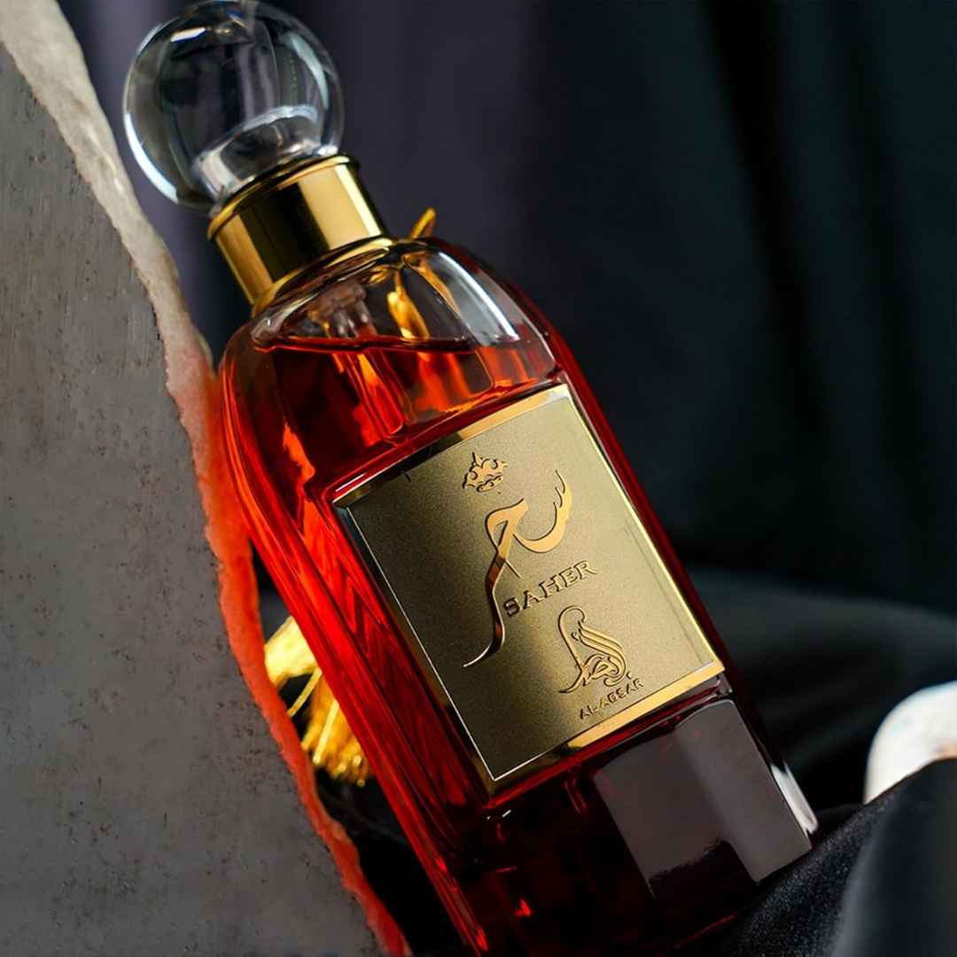 Red perfume bottle with gold cap and label on a dark background. Saher by Al Absar Womens Perfume