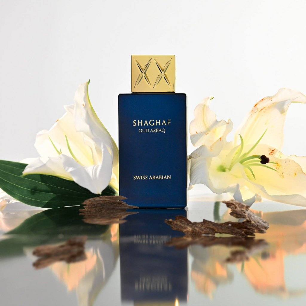 Shaghaf Oud Azraq perfume bottle with white flowers on a reflective surface