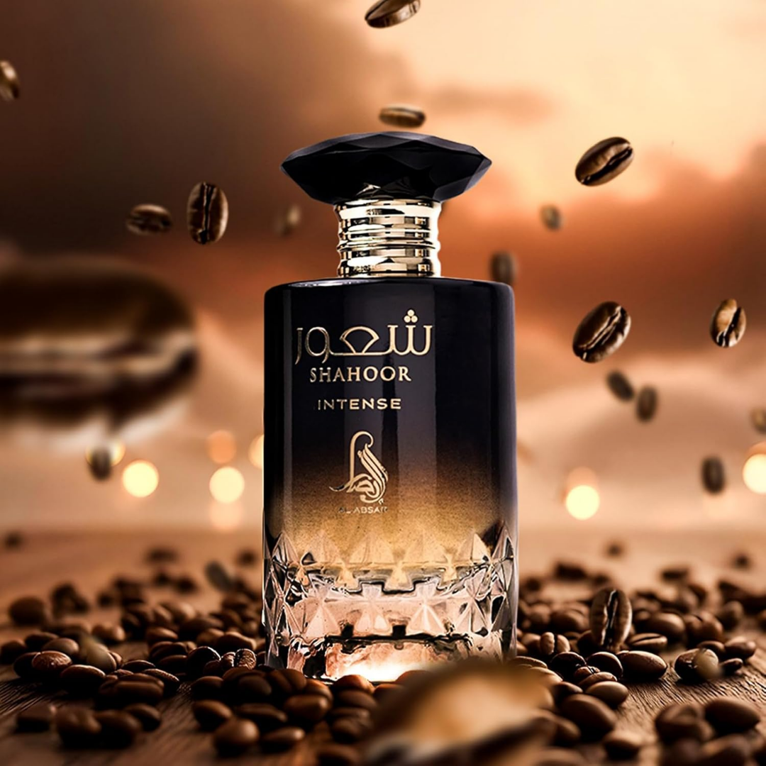 Perfume bottle labeled 'Shahoor Intense' surrounded by coffee beans on a wooden surface.