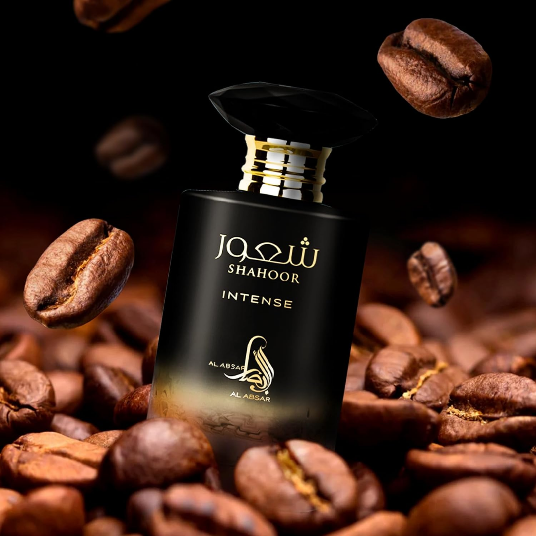 Perfume bottle labeled 'Shahoor Intense' surrounded by coffee beans on a dark background