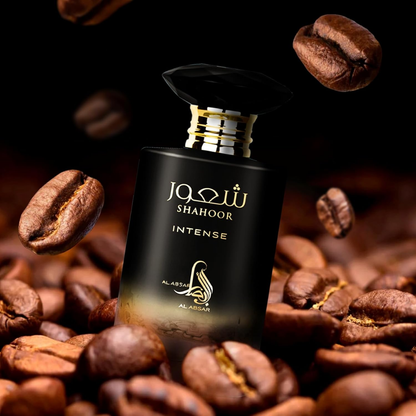 Perfume bottle labeled 'Shahoor Intense' surrounded by coffee beans on a dark background